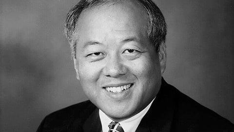 a man wearing a suit and tie smiling at the camera