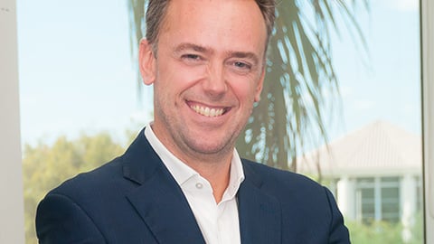 a man wearing a suit and tie smiling at the camera