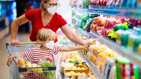 a person standing in front of a store filled with lots of food