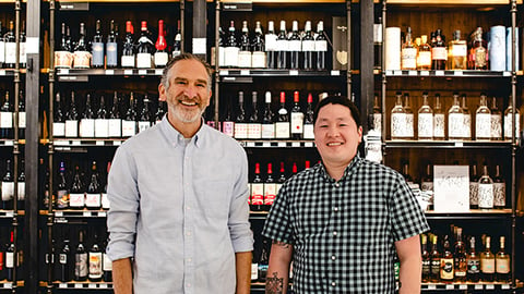 a man standing next to a bottle of wine in front of a store