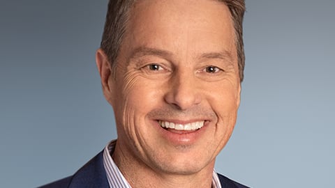 a man wearing a suit and tie smiling at the camera