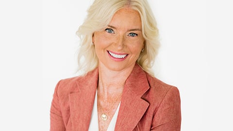 Carolyn Everson wearing a suit and tie smiling at the camera