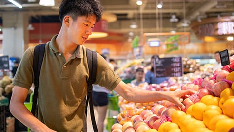 a man standing in front of a fruit stand