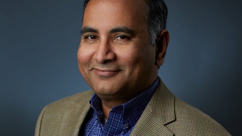 a man wearing a suit and tie smiling and looking at the camera