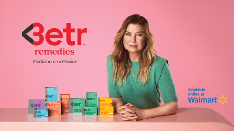 Ellen Pompeo sitting at a table with a laptop and smiling at the camera