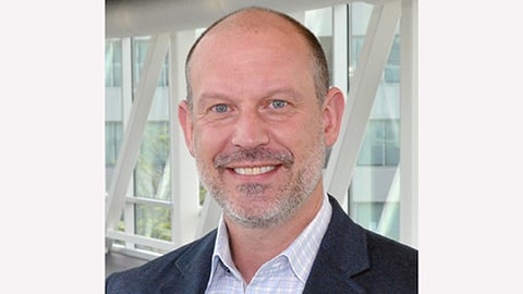 a man wearing a suit and tie smiling at the camera