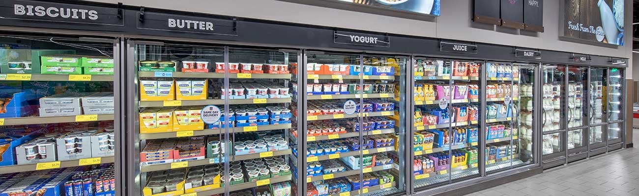 a bank of refrigerated product cases holding dairy products inside of an Aldi store