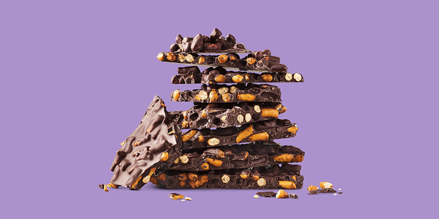 a stack of prezel-filled chocolate bark on a purple background