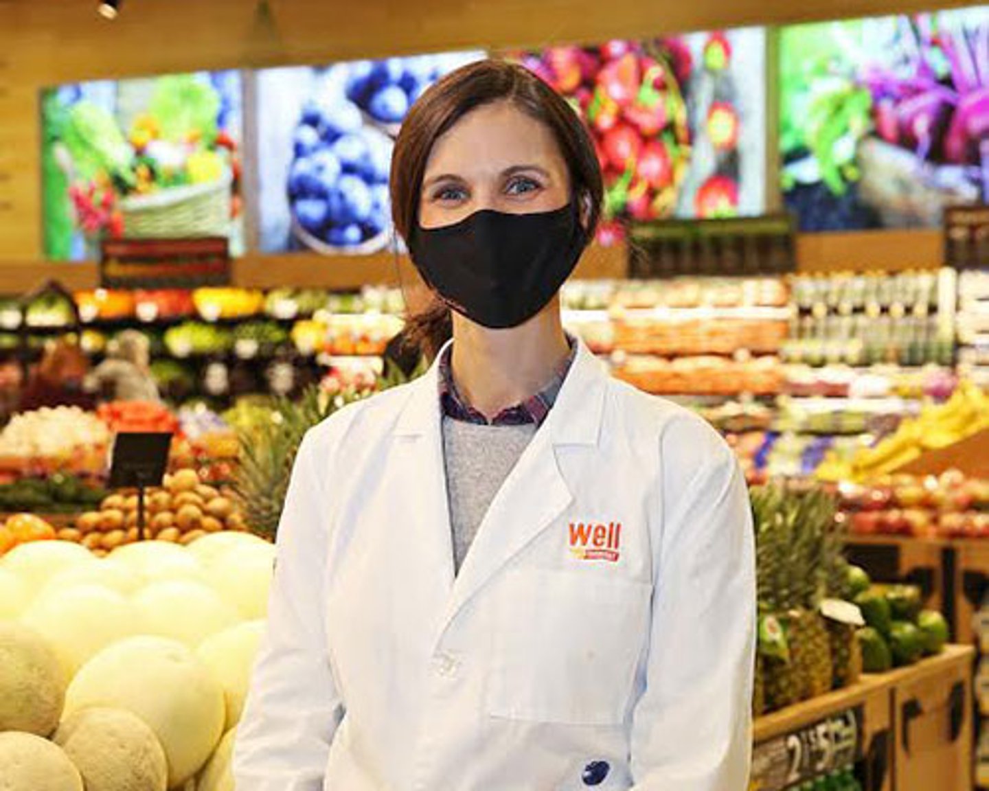 a man standing in front of a store filled with lots of fresh produce