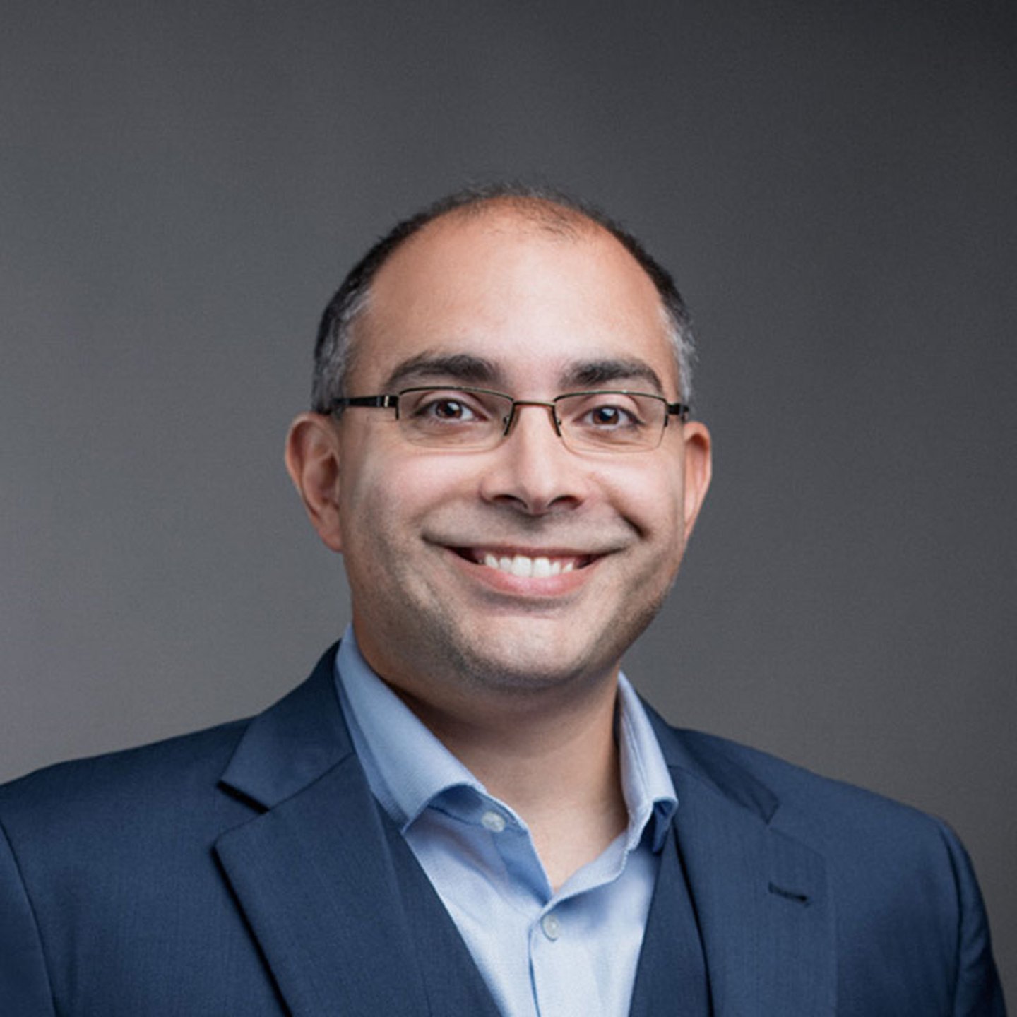 a man wearing a suit and tie smiling at the camera