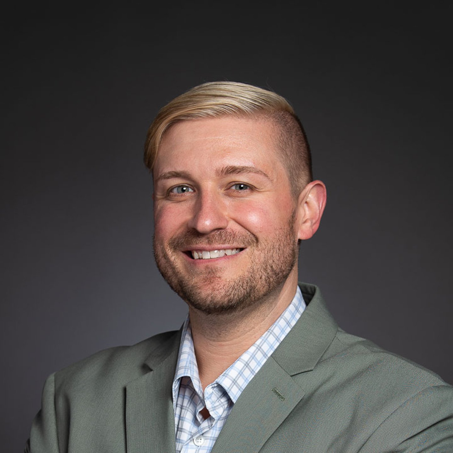 a man wearing a suit and tie smiling and looking at the camera