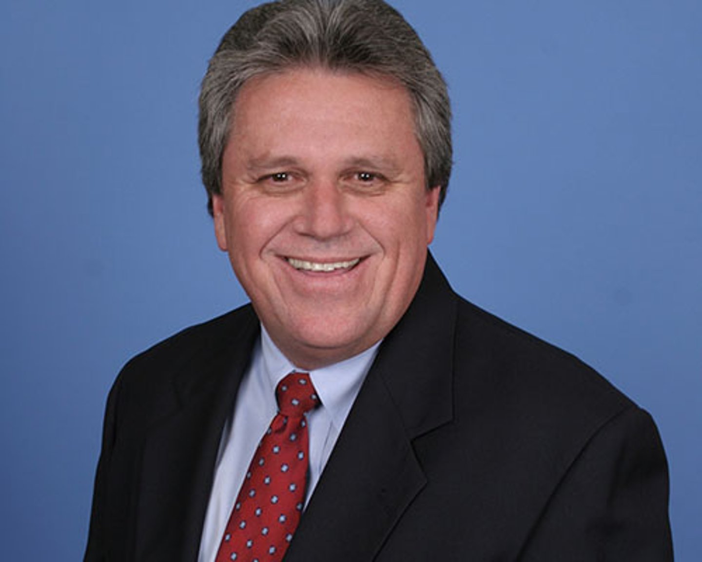 a man wearing a suit and tie smiling at the camera