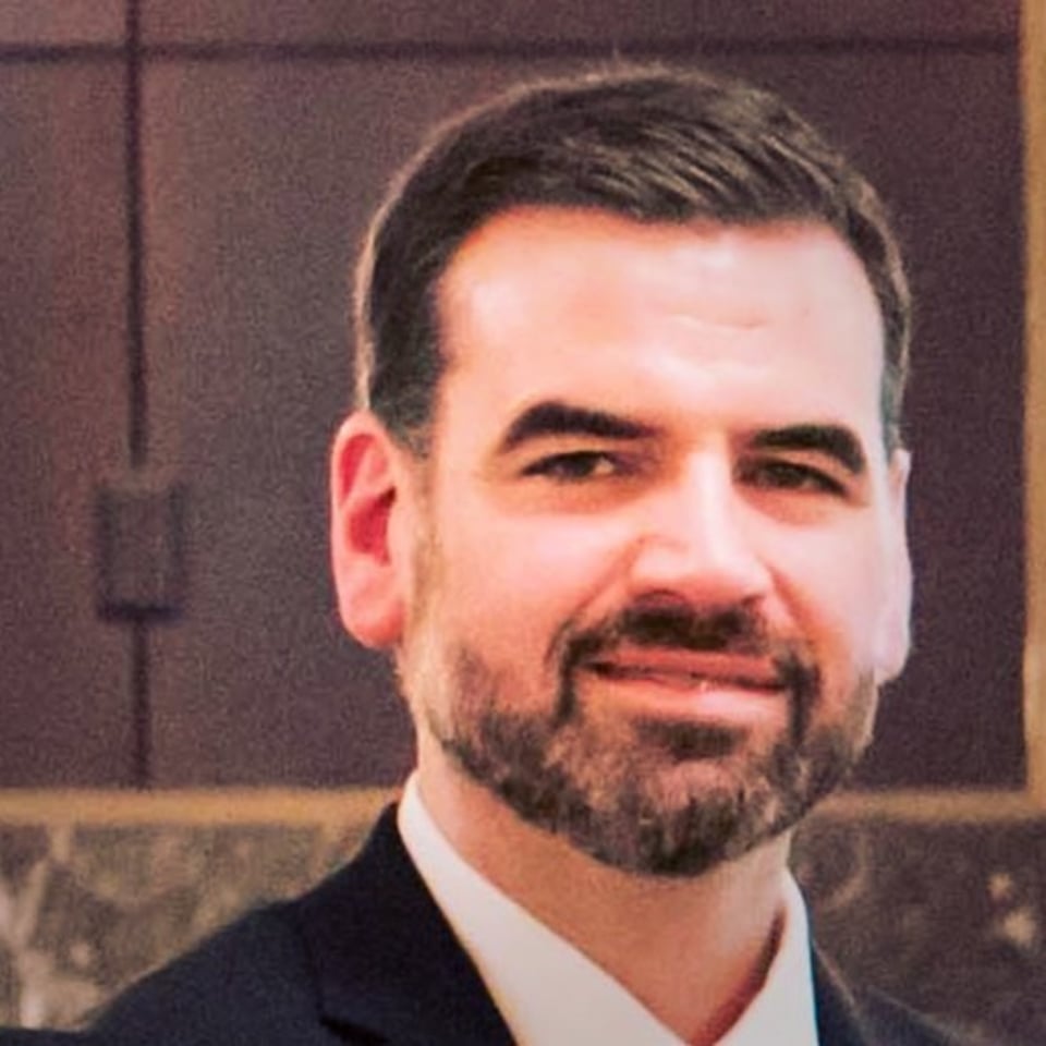 a man wearing a suit and tie smiling at the camera