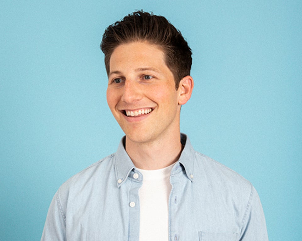 a man wearing a blue shirt and smiling at the camera