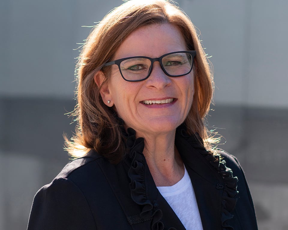 a woman wearing glasses and smiling at the camera