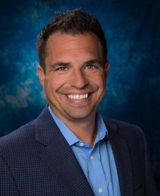 a man wearing a suit and tie smiling at the camera