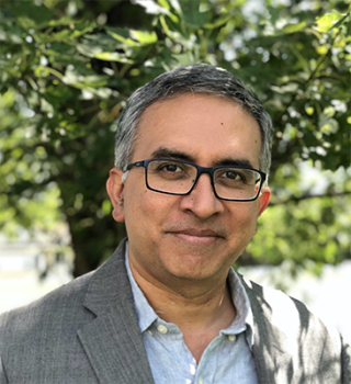 a man wearing glasses and smiling at the camera