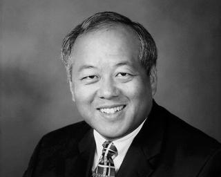 a man wearing a suit and tie smiling at the camera