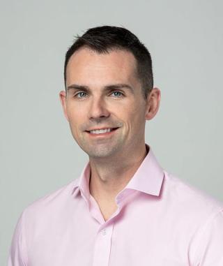 a smiling man wearing a pink shirt