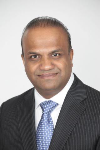 a man wearing a suit and tie smiling at the camera