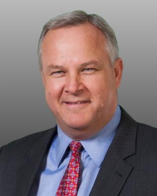 a man wearing a suit and tie smiling at the camera