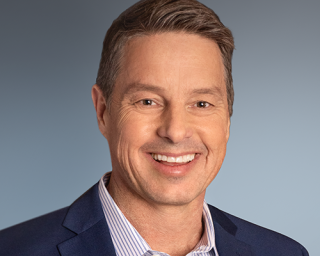 a man wearing a suit and tie smiling at the camera