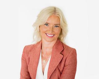 Carolyn Everson wearing a suit and tie smiling at the camera