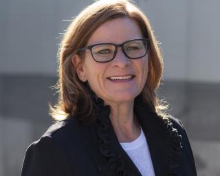 a woman wearing glasses and smiling at the camera