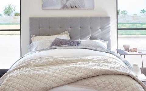 a made bed in a bedroom next to a window