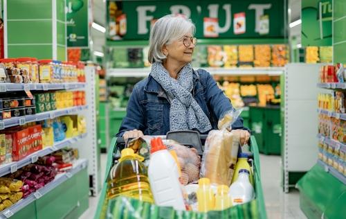 Woman shopping while pushing a full grocery cart
